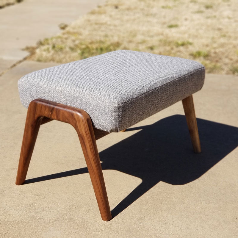 Hand sculpted walnut ottoman with grey fabric.